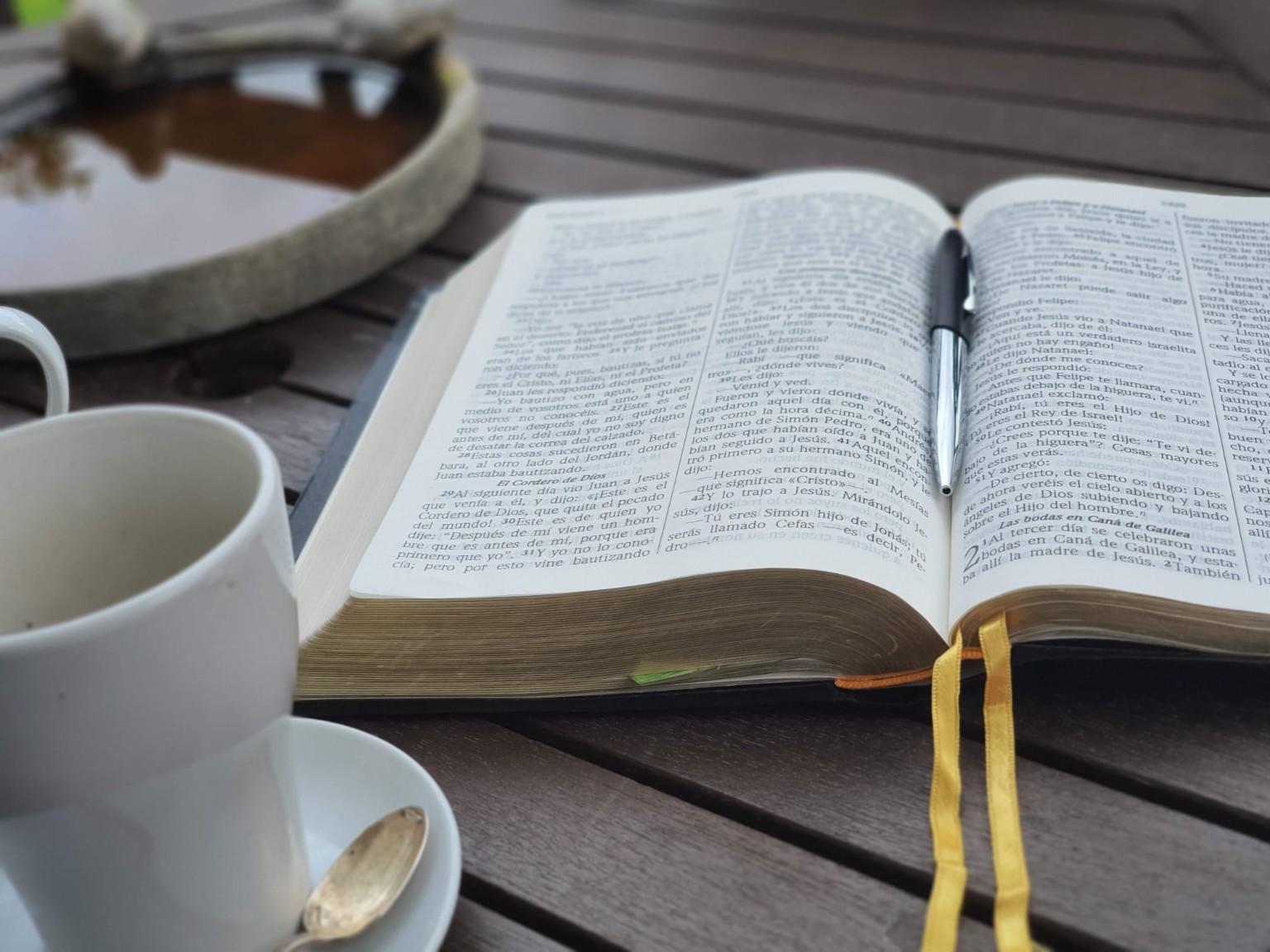 Biblia abierta sobre una mesa junto a una taza de café