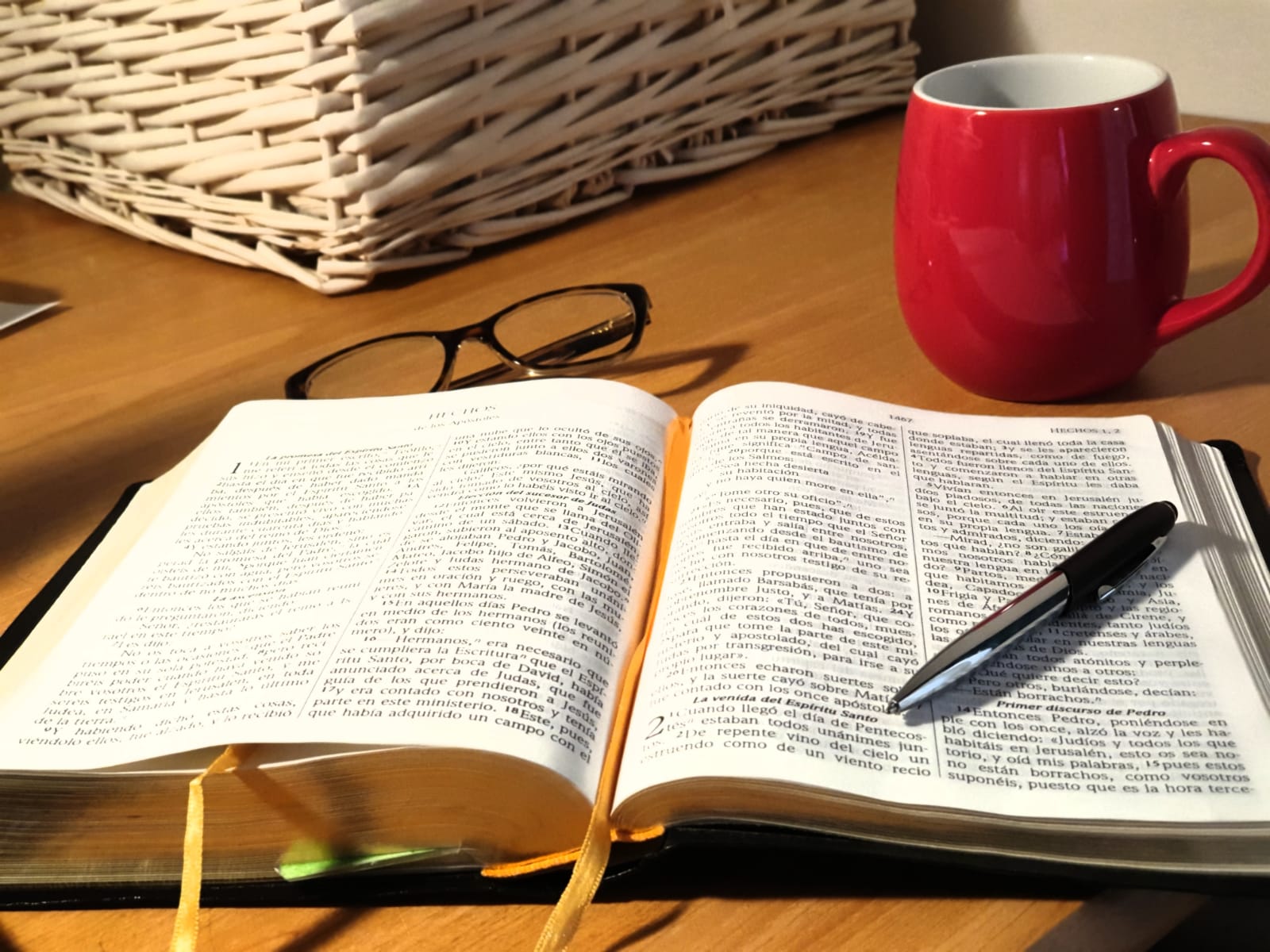 Biblia abierta, gafas y taza roja